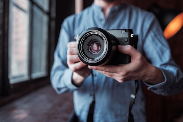 MOSCOU, RÚSSIA, 14 DE MARÇO DE 2019 Fujifilm GFX50s Camera Fujifilm Mirrorless Closeup da mão segurando a câmera Câmera Mirrorless close-up na mão de um jovem em um fundo de estúdio