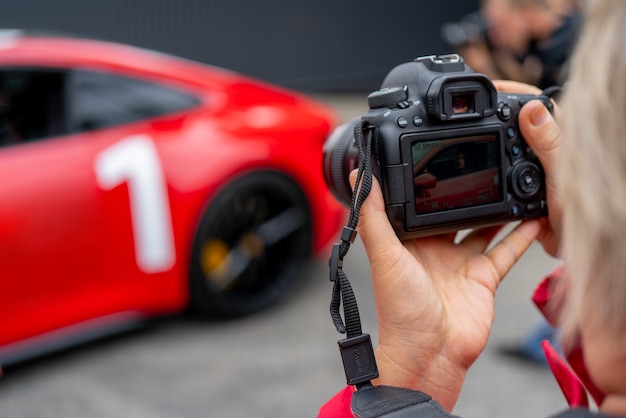 Moscú. Rusia. 13 de agosto de 2021 Fotógrafo y carro rojo. Sesión de fotos profesional de un coche rojo. El fotógrafo tiene la cámara en la mano.