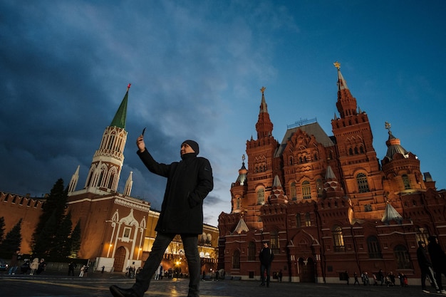 Moscú, Rusia - 24 de octubre de 2021: Hombre con un teléfono inteligente entre el Museo Histórico y la Torre Nikolskaya.