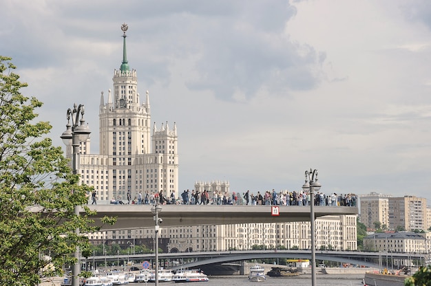 MOSKAU, RUSSLAND - 6. Juni 2021: Blick auf das Hochhaus am Kotelnicheskaya-Damm und die schwimmende Brücke im Zaryadye-Park in Moskau