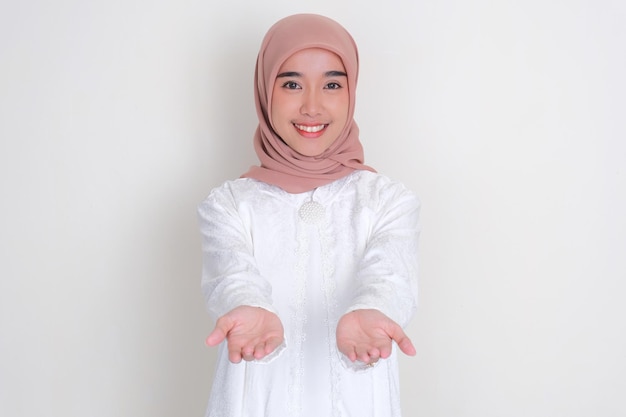 Moslemische asiatische Frau lächelt in die Kamera mit Händen, die etwas geben
