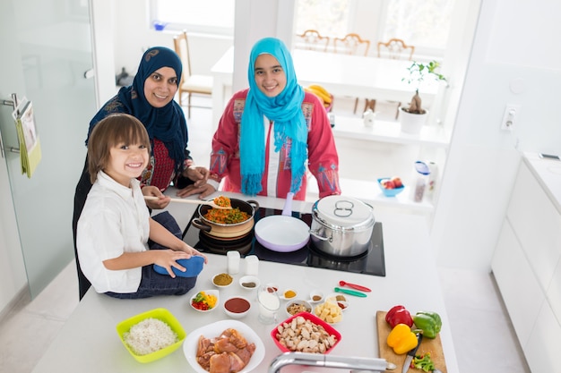 Moslemische traditionelle Frau mit kleinem Sohn in der modernen weißen Küche