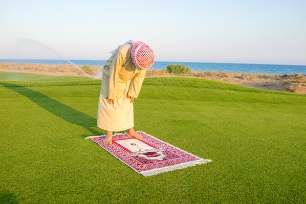 Moslemischer arabischer Junge, der auf grüner Wiese betet