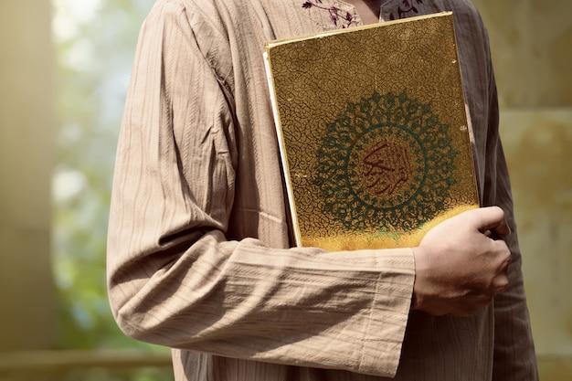 Moslemischer Mann, der Quran hält