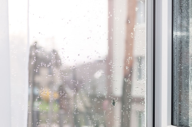 Mosquitera en un marco de ventana de plástico después de la lluvia