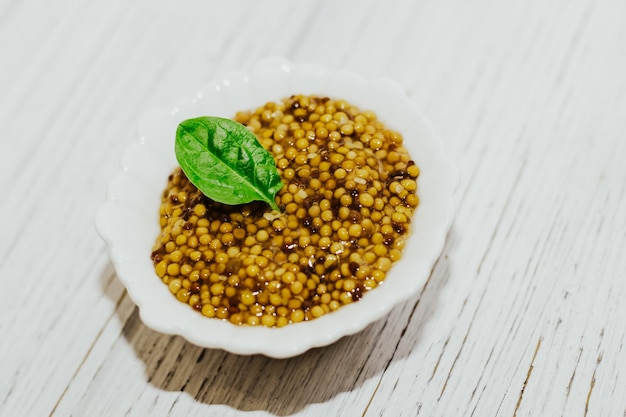 Mostarda em grãos com molho de salada de folhas verdes em uma tigela branca