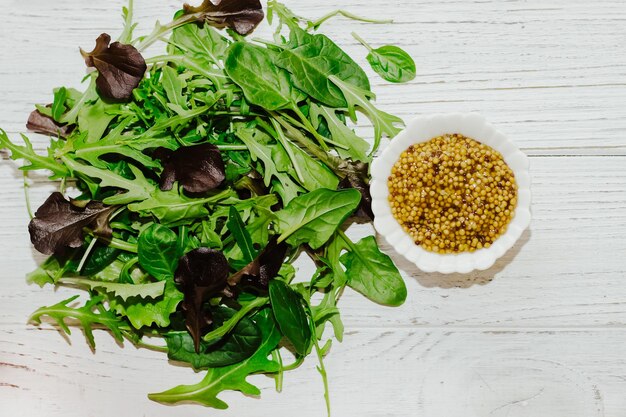 Mostaza de grano con aderezo de ensalada de hojas verdes en un tazón blanco