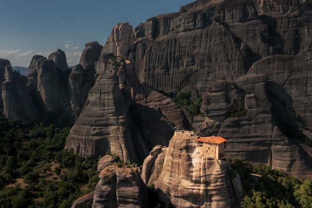 Mosteiro cristão brilhantemente iluminado no penhasco cercado por falésias de montanha ao pôr do sol Meteora Grécia