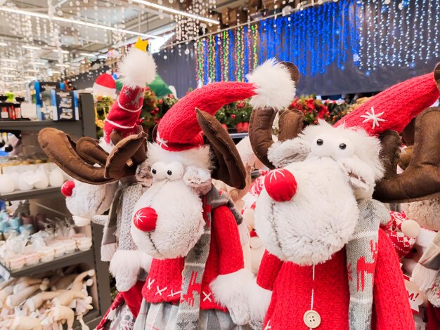 El mostrador del centro comercial vende juguetes de peluche para Navidad con gorras rojas y letras.