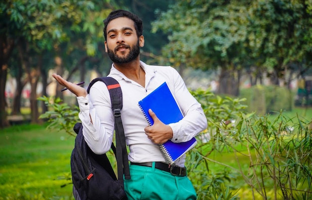 Mostrando algo usando a mão imagens de menino indiano estudante universitário indiano