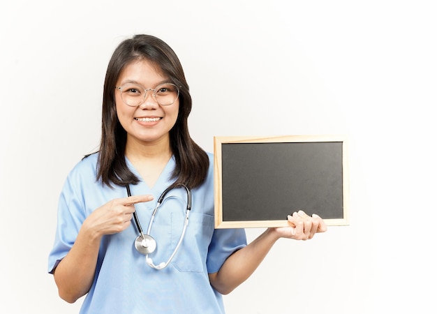 Mostrando apresentando e segurando o quadro-negro em branco do jovem médico asiático isolado no fundo branco