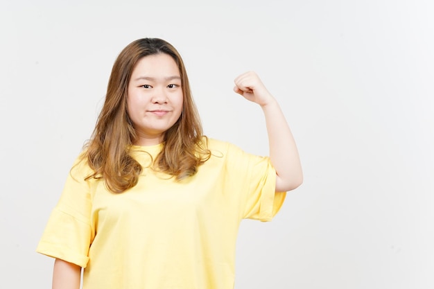 Mostrando brazos de fuerza de hermosa mujer asiática vistiendo camiseta amarilla aislado sobre fondo blanco.