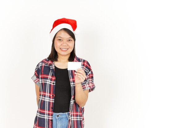 Mostrando e segurando o cartão de crédito em branco de uma linda mulher asiática vestindo camisa xadrez vermelha e chapéu de Papai Noel