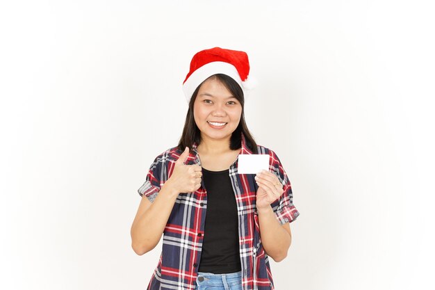 Mostrando e segurando o cartão de crédito em branco de uma linda mulher asiática vestindo camisa xadrez vermelha e chapéu de Papai Noel