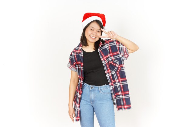 Mostrando o sinal de paz ou vitória de uma bela mulher asiática vestindo camisa xadrez vermelha e chapéu de Papai Noel