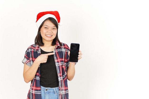 Mostrando y presentando la pantalla del teléfono inteligente en blanco de la mujer asiática con camisa a cuadros roja y gorro de Papá Noel