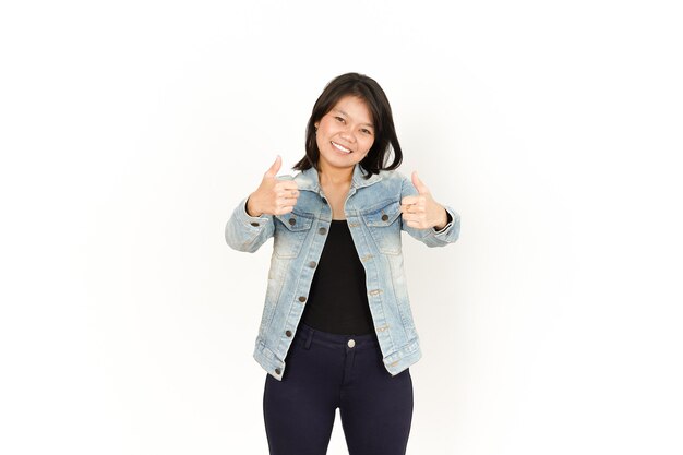 Mostrando los pulgares para arriba de la hermosa mujer asiática con chaqueta de jeans y camisa negra aislado en blanco