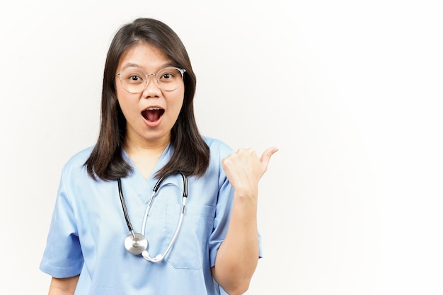 Mostrando y señalando el producto con el pulgar del joven médico asiático aislado sobre fondo blanco.