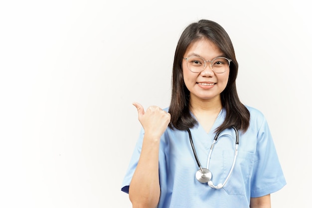 Mostrando y señalando el producto con el pulgar del joven médico asiático aislado sobre fondo blanco.