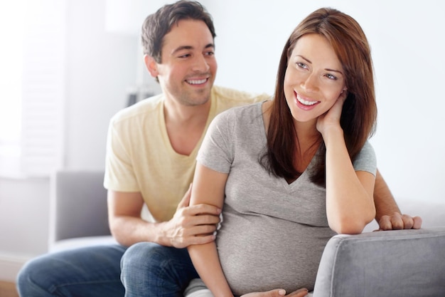 Mostrando su apoyo todo el camino Atractiva pareja joven esperando sentada en su sala de estar