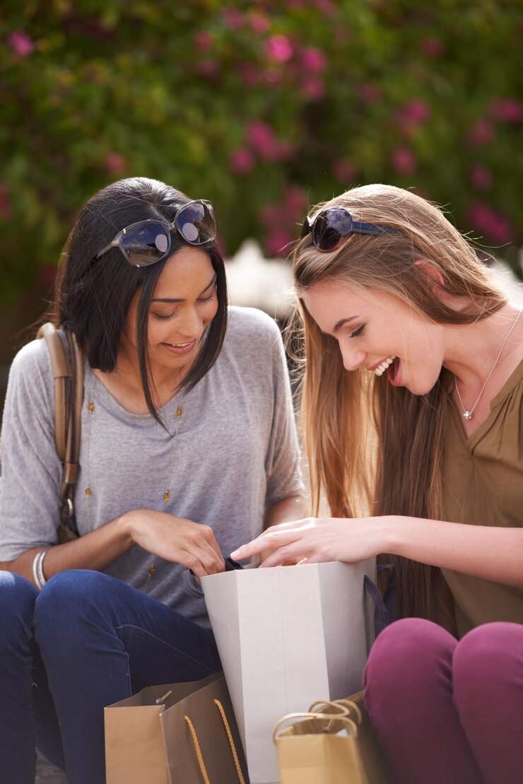 Foto mostrar e contar duas jovens admirando seus achados de compras