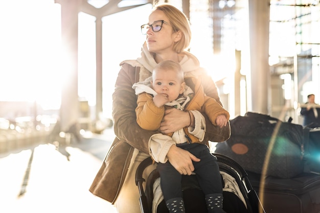 Foto motherat viajando com seu bebê bebê menino criança caminhando empurrando carrinho de bebê e carrinho de bagagem em