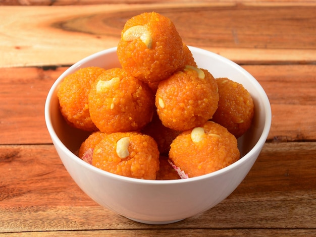 Motichoor Laddoo o Bundi Laddoo hecho de finos dulces en forma de bola bundi populares en el subcontinente indio cocinados con azúcar ghee servidos sobre un plato blanco sobre un fondo rústico de madera enfoque selectivo
