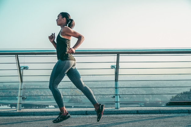 Motivada linda senhora desportiva correndo na ponte da cidade sozinha. Banner do site