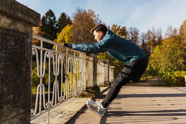 Motivation für einen Sportläufer im Herbst Training eines männlichen Trainers, um die Beine aufzuwärmen