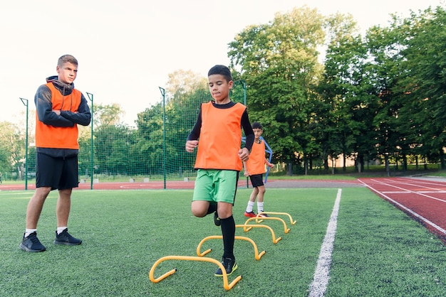 Motivierte Fußballspieler führen Laufübungen durch, um Hindernisse zu überwinden