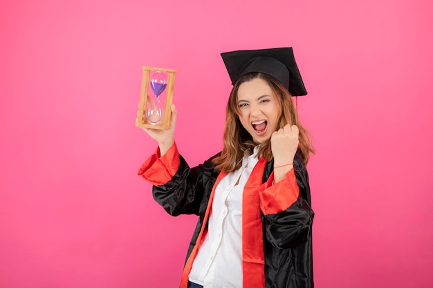 Motivierte junge schöne Studentin, die Zeitschaltuhr hält und ihre Faust drückt. Foto in hoher Qualität