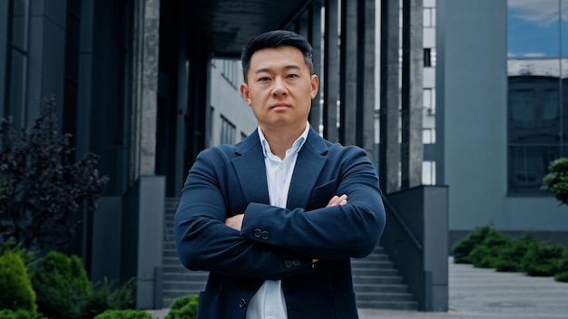 Motivierter ernster starker lächelnder positiver erwachsener asiatischer koreanischer Mann mittleren Alters Unternehmermanager