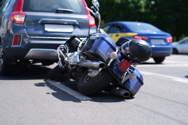 Foto moto azul deitada na estrada perto do carro.