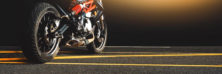Moto estacionada sozinha em uma estrada de asfalto à noiteConceito panorâmico de moto