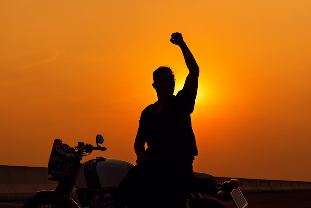 Moto no caminho de volta em uma viagem de verão, homem de silhueta andando de moto, conceito de liberdade.