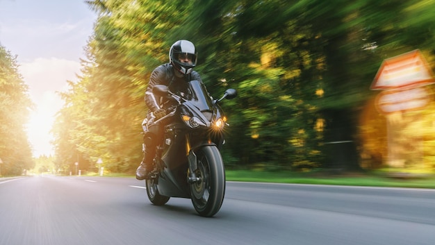 Motocicleta andando na estrada da floresta no verão dirigindo na estrada vazia em uma viagem de moto copyspace para seu texto individual