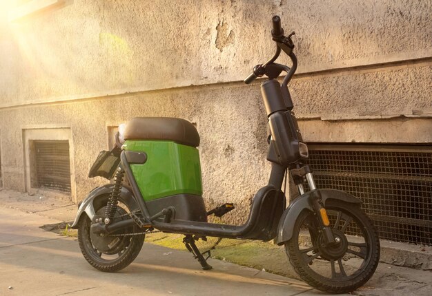 Foto una motocicleta eléctrica está estacionada en la ciudad. bicicleta eléctrica verde en la acera al atardecer.