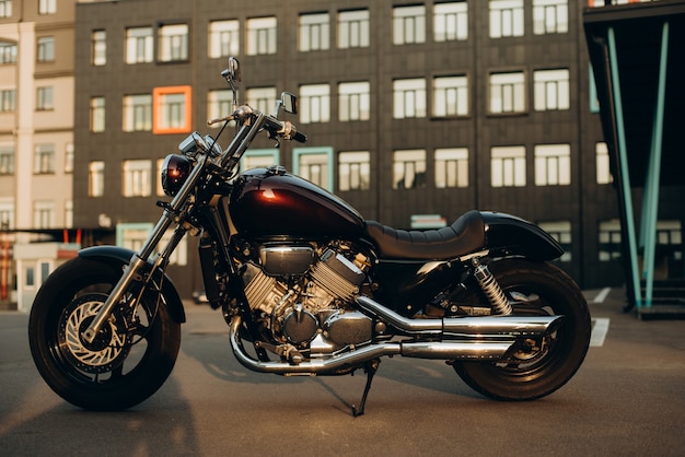 Una motocicleta en un estacionamiento a la cálida luz de un atardecer. Elegante moto chopper personalizada con detalles cromados. Enfoque selectivo suave.