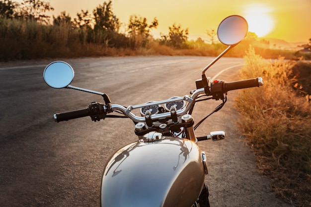 Motocicleta de estilo clásico en carretera con puesta de sol