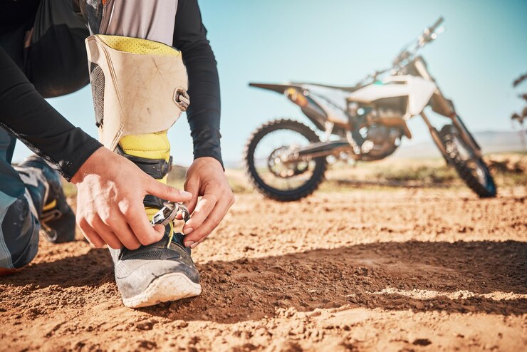Foto motocicleta extrema y hombre atando cordones en la naturaleza para unas vacaciones de aventura y una carrera en el campo comience a viajar y esté listo para andar en bicicleta con zapatos para un viaje en moto por un camino de tierra por la libertad