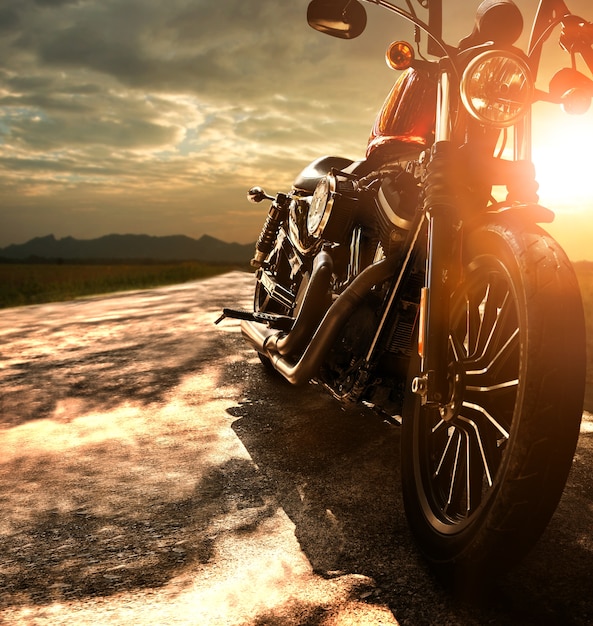 Foto motocicleta retro velha que viaja na estrada secundária contra a luz bonita do céu do por do sol