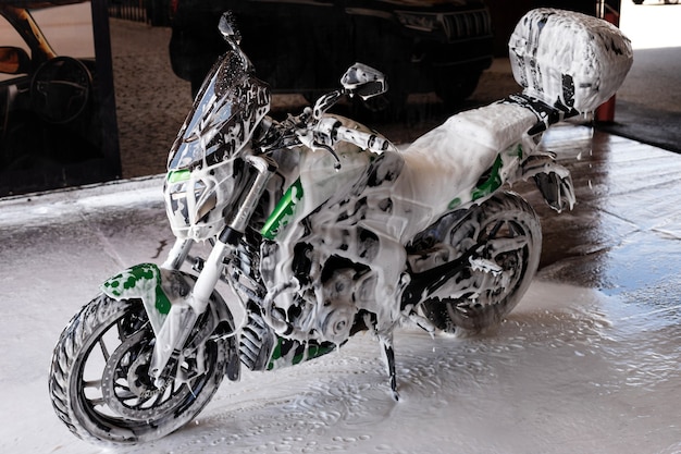 Foto motocicleta verde en espuma en el lavado de autos