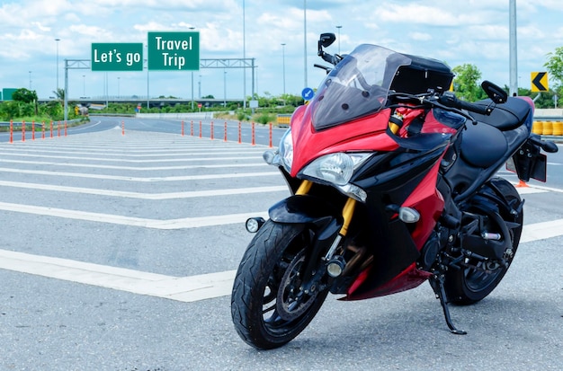 Motocicleta vermelha estacionada na estrada com a mensagem Vamos viajar viagem em fundo de sinal verde
