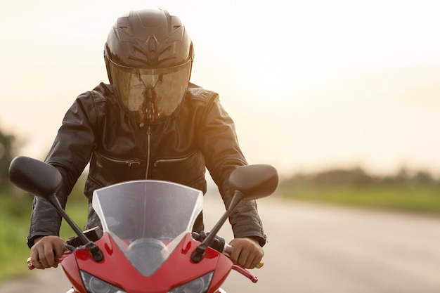 Foto motociclista bonito vestindo jaqueta de couro e segurando o capacete na estrada