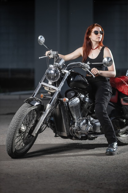 Motociclista chica posando sexualmente en motocicleta en la ciudad de noche