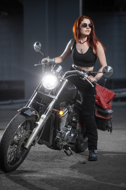 Motociclista chica posando sexualmente en motocicleta en la ciudad de noche