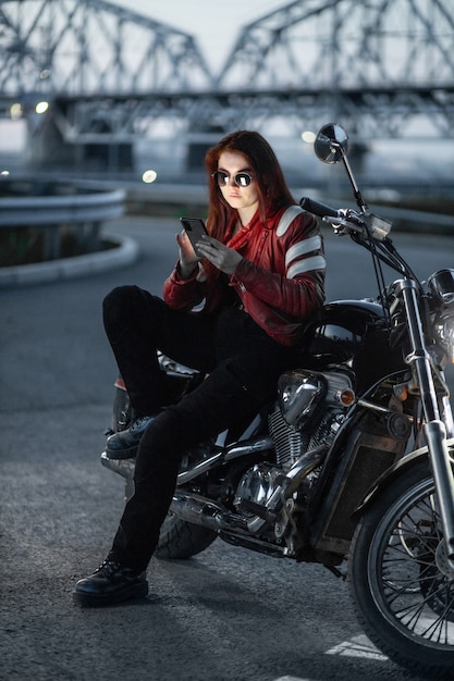 Motociclista chica posando sexualmente en motocicleta en la ciudad de noche