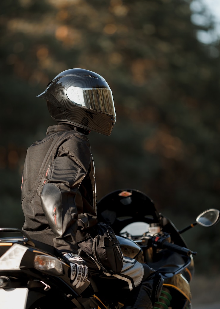 Foto motociclista com um capacete e equipamento de proteção de couro sentado em uma motocicleta, uma motocicleta esportiva rápida