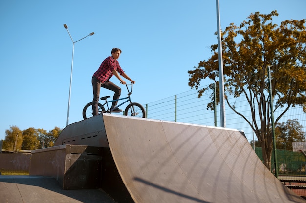 Motociclista de bmx fazendo truque, adolescente em treinamento no skatepark. esporte radical de bicicleta, exercícios de ciclismo perigosos, passeios de rua de risco, ciclismo no parque de verão