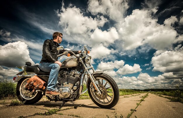 Motociclista de óculos escuros e jaqueta de couro na estrada